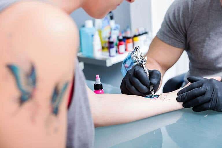 woman getting tattoo on her wrist